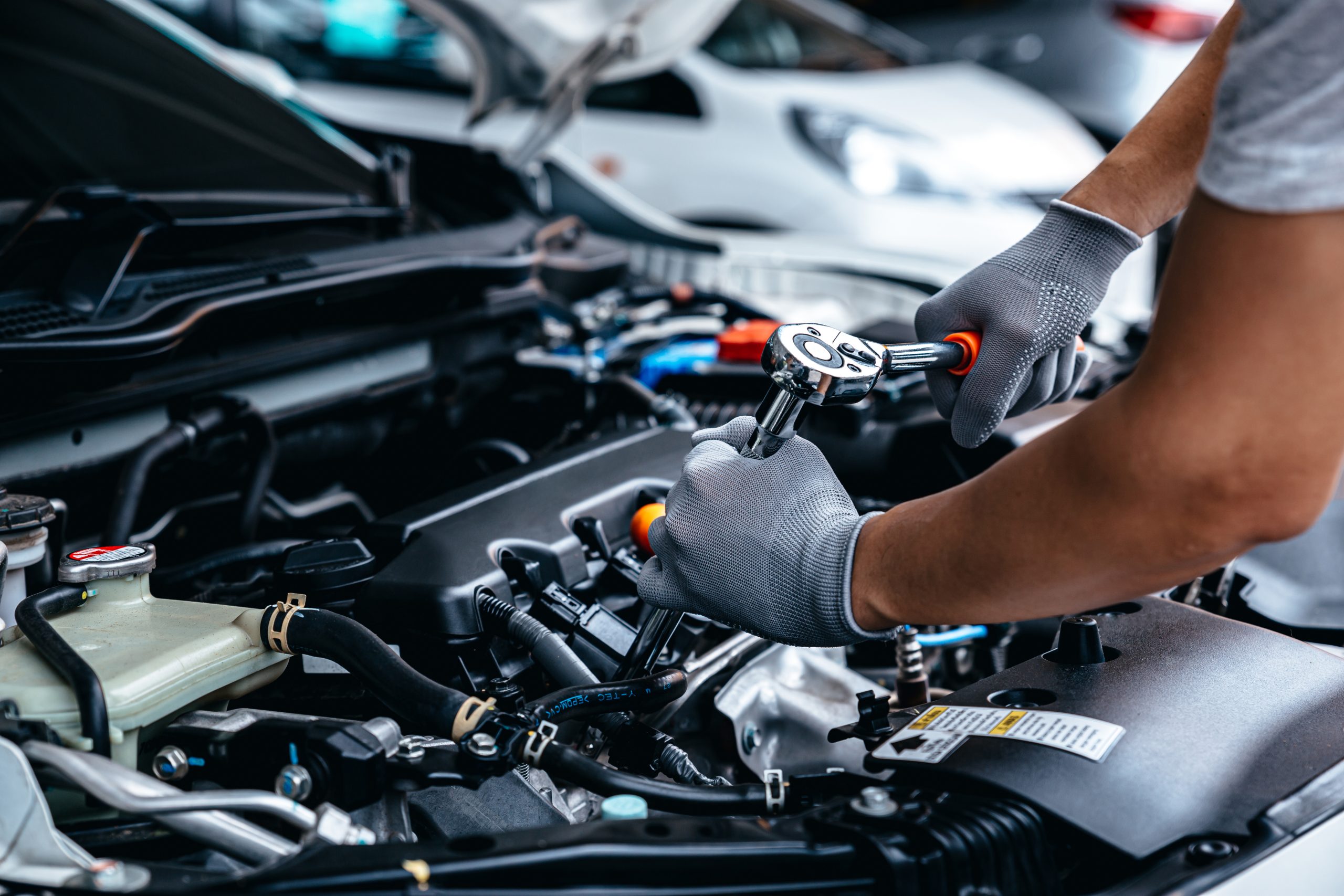 Mechanic using wrench while working on car engine at garage work